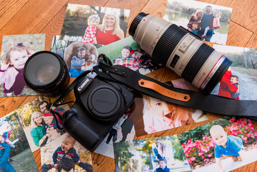 Printed photos of the Thornhill family scattered under Elle Bea Photography's camera equipment. Life cycle, lifestyle photography in prints.