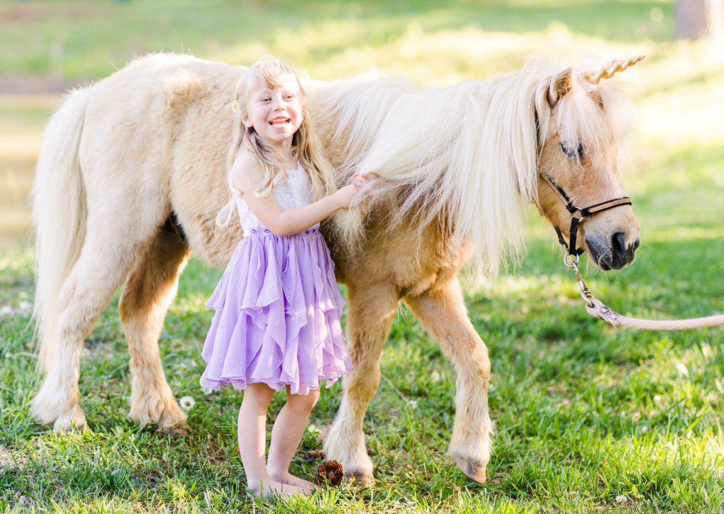 Little girl laughs with Wesley the unicorn in a photo by Elle Bea Photography in Chickamauga, Georgia near Chattanooga, Tennessee