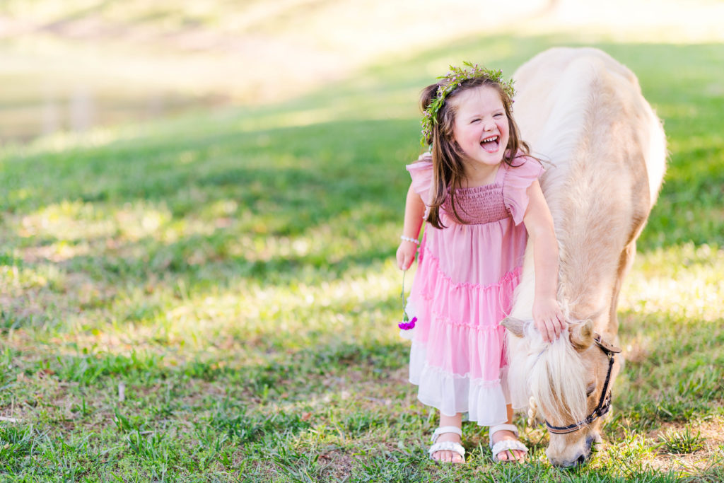 Little girl laughs with Wesley the unicorn in a photo by Elle Bea Photography in Chickamauga, Georgia near Chattanooga, Tennessee