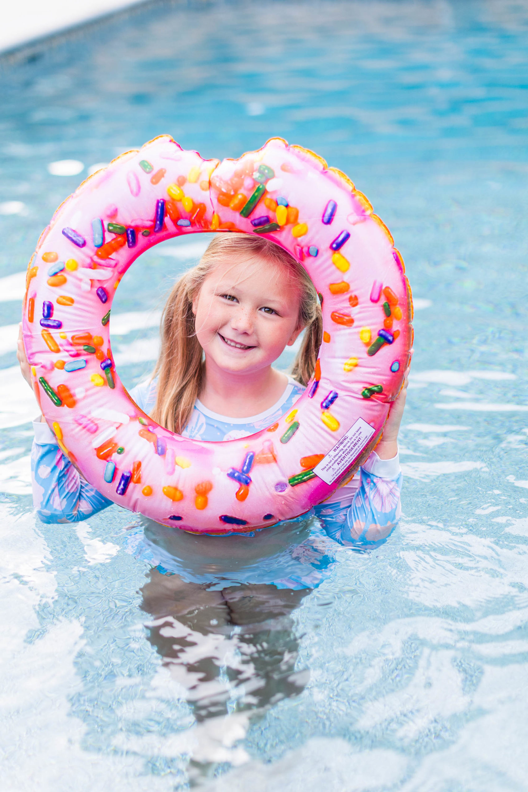 Happy girl poses with donut float at Pool Party Mini Sessions in Rossville, Georgia by local photographer Elle Bea Photography