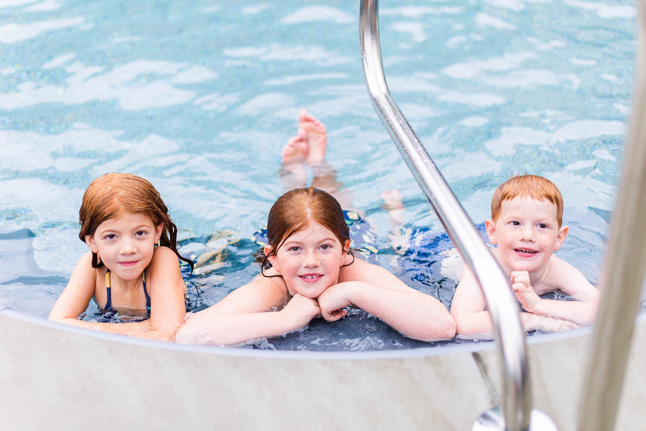 Happy kids pose in the pool at Pool Party Mini Sessions in Rossville, Georgia by local photographer Elle Bea Photography