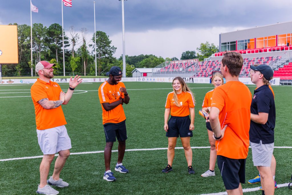Coaches laugh together on the field at Soccer Shots Chattanooga hosts Family Night 2022 at CHI Memorial Stadium, home of the Red Wolves