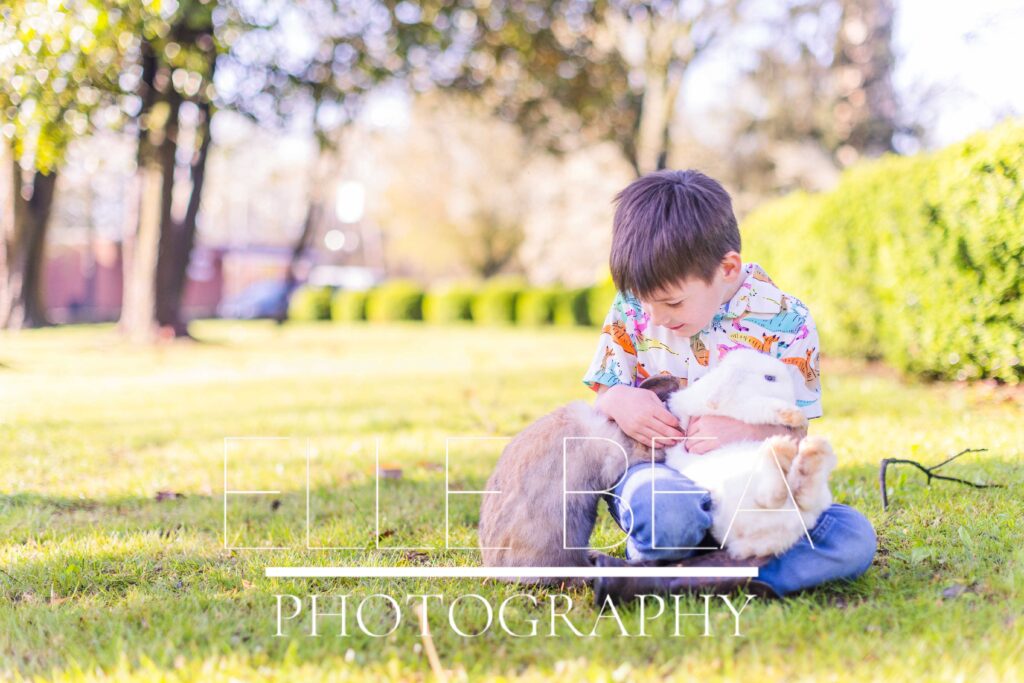 Boy lets slip a brown bunny while also holding a white bunny on the lawn at live bunny mini sessions in Chickamauga, Georgia