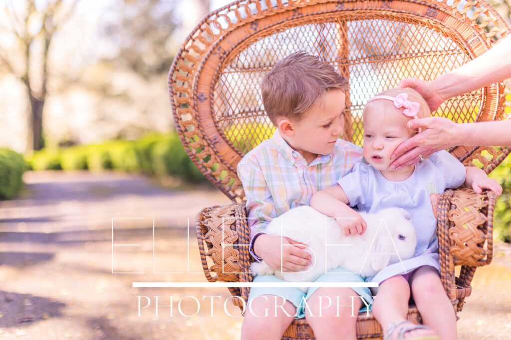 Brother and sister try to pose with white bunny at live bunny mini sessions in Chickamauga, Georgia