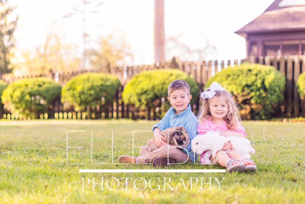Brother holds brown bunny while sister holds white bunny and they smile at the camera at live bunny mini sessions in Walker County, Georgia