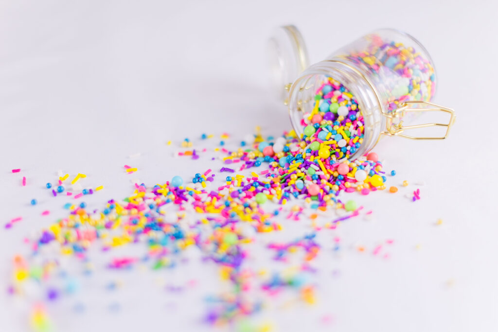 Spilled sprinkles in glass and gold jar branding image