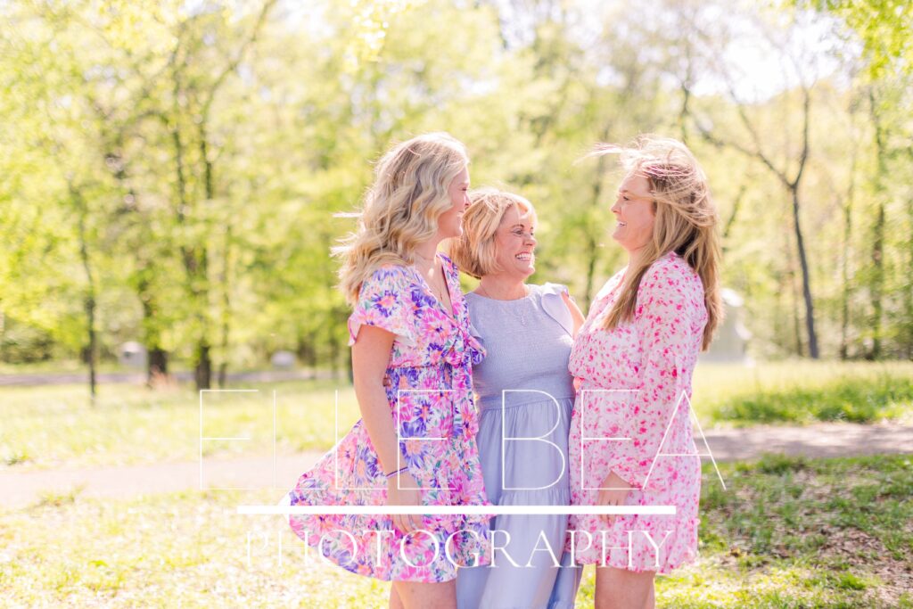 Mom and adult daughters laugh together while looking perfectly styled for their family mini session photos