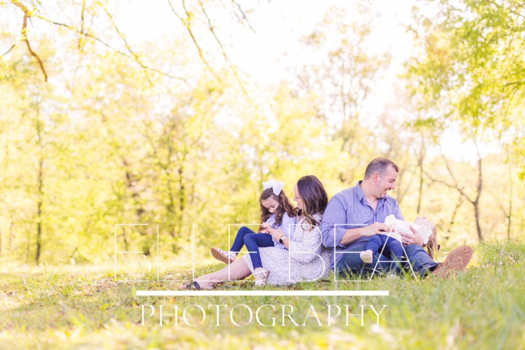 Styling for family mini sessions example - family of mom, dad, big sister, and little sister laugh together in the grass at the battlefield in Chickamauga, Georgia.