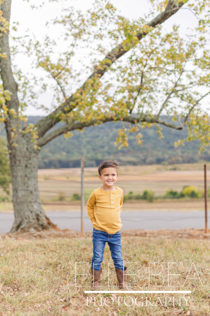 Little boy poses and smiles for photo on a cloudy photoshoot day in Chickamauga, Georgia