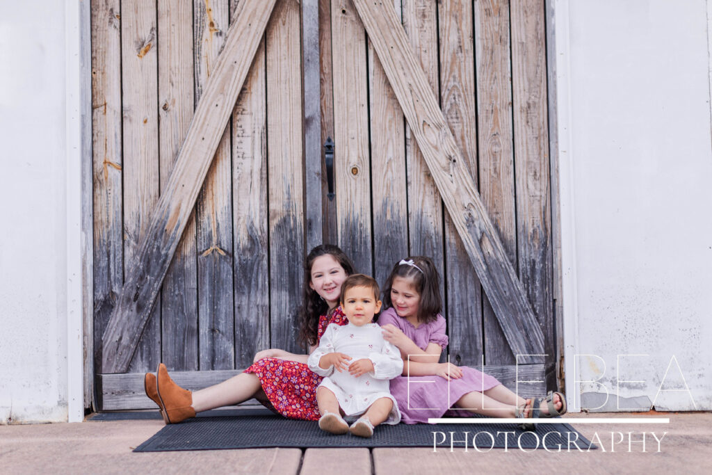 Sisters laugh in front of wood barn doors at Mountain Cove Farms