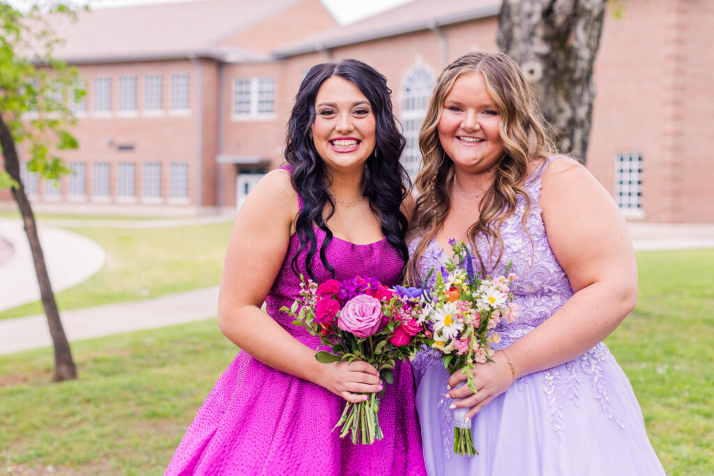 Two girls smile at the camera in their prom dresses in front of Gordon Lee High School in Chickamauga, Georgia
