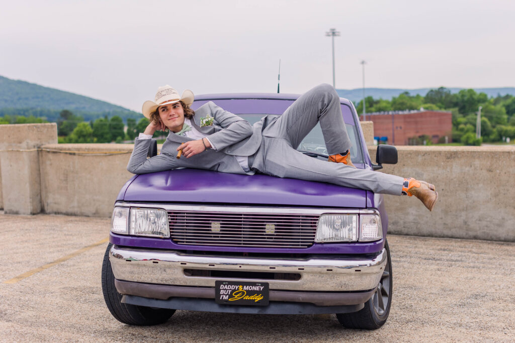 Prom student poses on top of his purple truck on the rooftop of the parking deck in Chattanooga, Tennessee in the iconic West Village